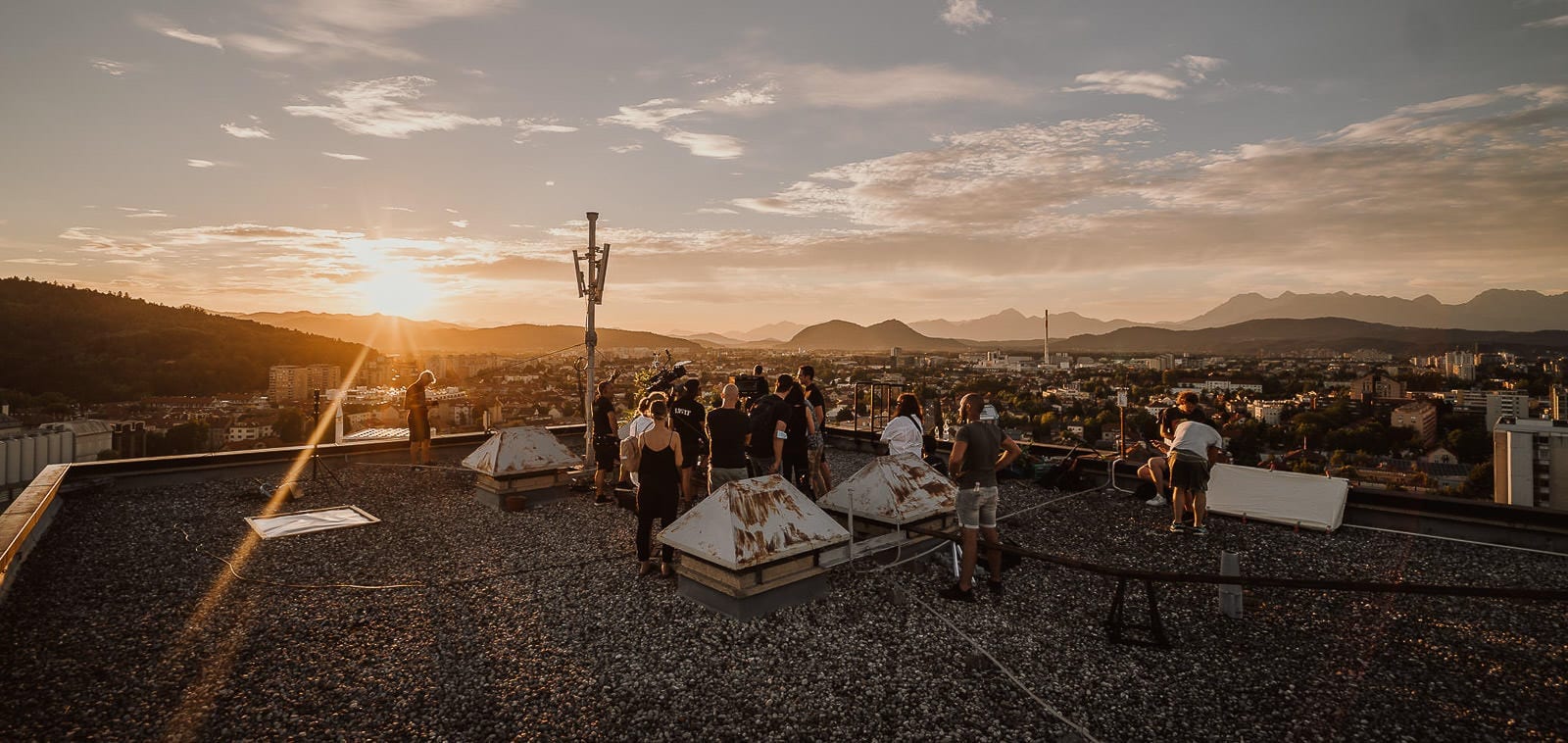 Squareme Triglav Skladi TV ads - production crew during filming on an urban rooftop overlooking Ljubljana at sunset
